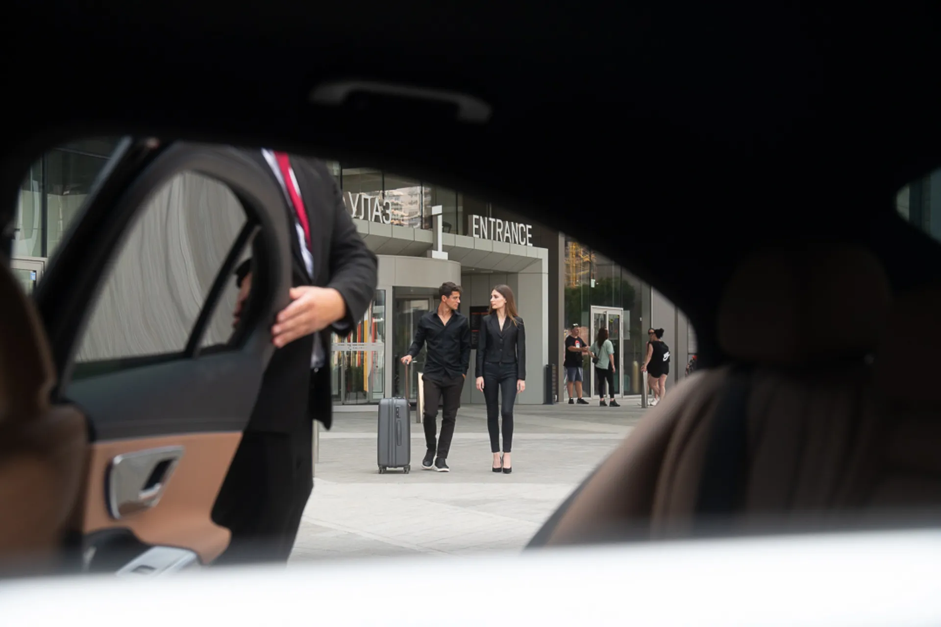 A chauffeur holds the rear door outside the terminal