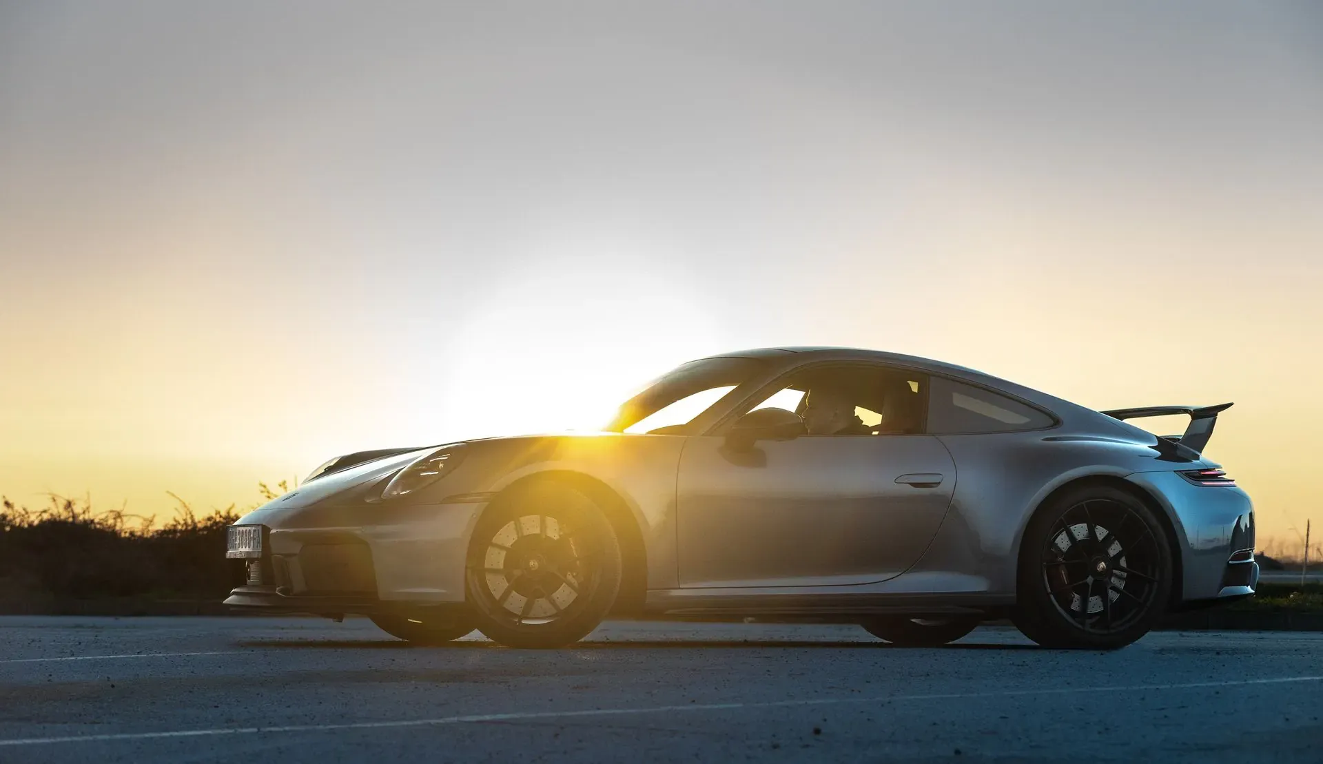 A silver Porsche 911 at sunset
